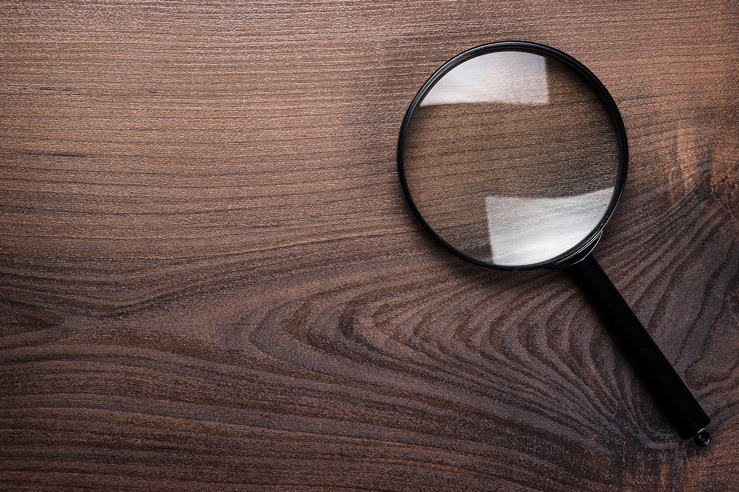 magnifying glass on the brown wooden background